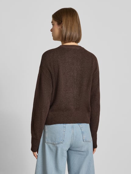 Frauenmodel trägt Cardigan mit Woll-Anteil Modell 'NATALIE' von JJXX in Braun, Strick-Optik, elastische Abschlüsse, Ganzkörperansicht Rückansicht.