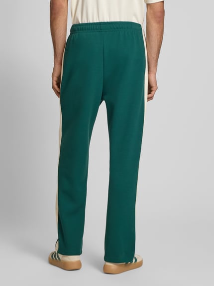 Männermodel trägt Straight Fit Sweatpants mit Logo-Stitching von KARL KANI in Dunkelgrün mit Elastischer-Material-Mix, Ganzkörperansicht Rückansicht.