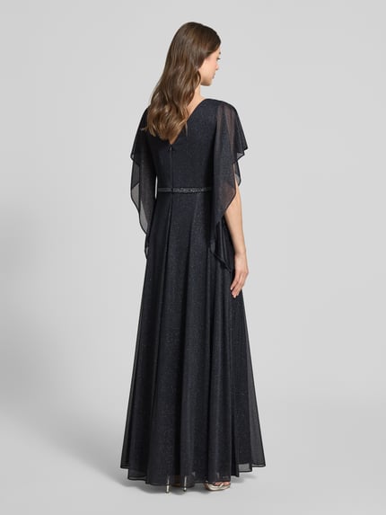 Frauenmodel trägt Maxikleid mit V-Ausschnitt und Ziersteinbesatz von Vera Mont in Glitzer-Optik, taillierte Passform, Volantärmel, Falten-Optik, Rückenlänge bei Größe 38: 133 cm, Brustweite 42 cm, Ärmellänge 24 cm, Ganzkörperansicht Rückansicht.