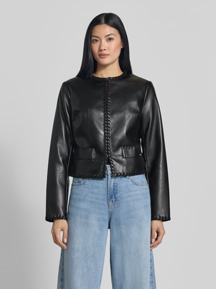 Frauenmodel trägt Jacke in Leder-Optik Modell 'LEONTINE' von GUESS, schwarz, Rundhalsausschnitt, Stitchings, Ganzkörperansicht von vorne.