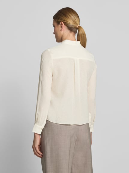 Vrouwenmodel draagt Regular Fit Schluppenbluse met Rüschen van Christian Berg Woman Selection, crèmekleur, lichte textuur, ruglengte 57 cm, mouwlengte 60 cm, detail knoopsluiting, lange mouwen, Ganzkörperansicht Rückansicht.