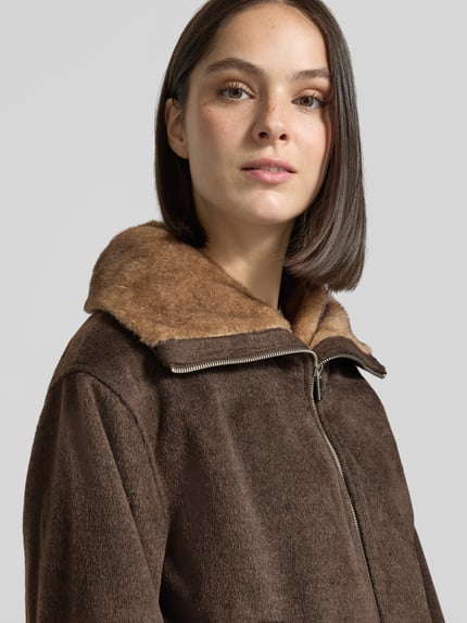 Vrouwenmodel draagt Blouson met Viskose-Anteil van zero in bruin, zachte textuur, kunstbontkraag, gevoerd, detailopname bovenlichaam.