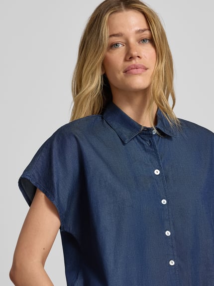Kobiece modelka nosi Relaxed Fit Bluse aus Lyocell-Baumwoll-Mix od Christian Berg Woman w stylu denim, niebieski kolor, kołnierzyk koszulowy, guzikowanie, Nahaufnahme górnej części ciała.