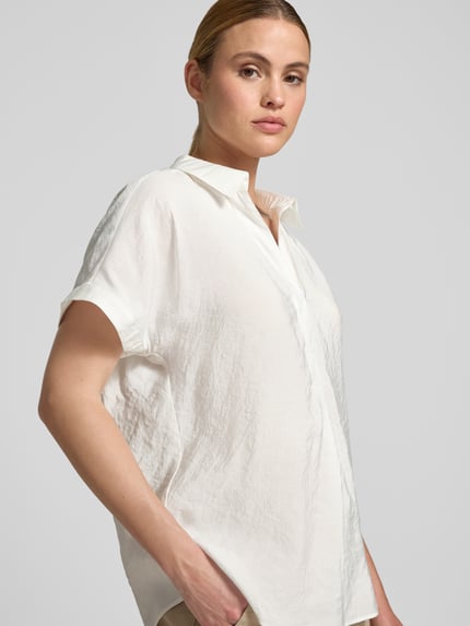 Modelka nosi Relaxed Fit Bluse aus Modal-Mix mit V-Ausschnitt od Betty Barclay, mieszanka modalu, kołnierzyk koszulowy, dekolt w serek, długość tyłu w rozmiarze 36: 64 cm, jasna, gładka faktura, widok z przodu, zbliżenie na górną część ciała.
