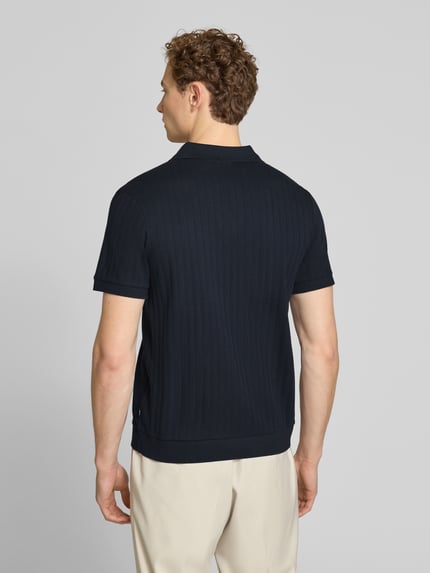 Męski model nosi Regular Fit Poloshirt mit V-Ausschnitt Modell 'Baronito' von JOOP! Collection z bawełny, fakturowany wzór, długość tyłu 69 cm, kolor ciemnogranatowy, Ganzkörperansicht Rückansicht.