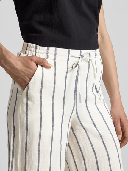 Frauenmodel trägt Straight Fit Leinenhose aus reinen Leinen Modell 'Callie' von MAC, weiß mit schwarzen Streifen, Nahaufnahme Oberkörper, verkürzte Passform, elastischer Bund mit Tunnelzug, reine Leinen-Textur.