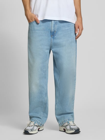 Männermodel trägt Relaxed Fit Jeans aus reiner Baumwolle Modell 'Brandon' von Carhartt Work In Progress, hellblaue Farbe, 5-Pocket-Design, Ganzkörperansicht von vorne, Kontext: Herren Jeans, Knopf- und Reißverschluss, Gürtelschlaufen, Bundweite Größe M 46 cm, Innenbeinlänge 73 cm.