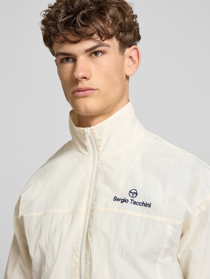 Männermodel trägt cremefarbene Regular Fit Jacke mit Stehkragen Modell 'Nayla' von SERGIO TACCHINI, Reißverschluss, Eingrifftaschen, elastische Abschlüsse, Nahaufnahme Oberkörper.