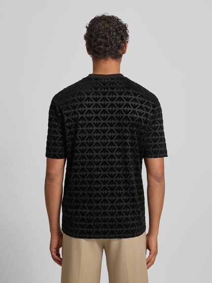 Männermodel trägt T-Shirt mit Label-Stitching von Emporio Armani, schwarz gemustert, Lyocell-Baumwoll-Mix, Regular-Fit, Ganzkörperansicht Rückansicht.