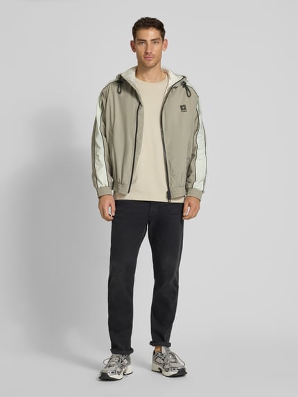 Mężczyzna prezentuje Regular Fit Jacke mit Kapuze Modell 'BAVO2621' od HUGO, jednolity kolor, długi rękaw, elastyczne wykończenia, logo, kieszenie boczne, zdjęcie całej sylwetki z przodu.