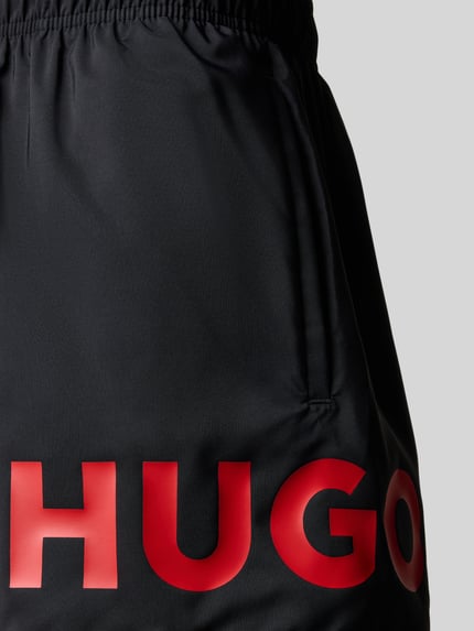 Produktfoto, Badeshorts mit Label Print Modell 'MAKAI' von HUGO, czarna popelina, czerwony nadruk logo, elastyczny pas, kieszenie boczne
