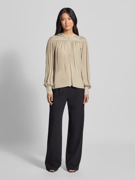 Frauenmodel trägt Regular Fit Langarmbluse aus reiner Viskose Modell 'C_Bethena' von BOSS Orange in Beige mit schwarzen Stoffhosen, Ganzkörperansicht von vorne.