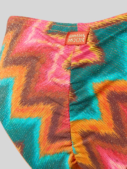 Produktfoto, Bikini-Slip mit Label-Detail Modell 'TUPA' von Banana Moon im bunten Zickzack-Muster mit feiner Textur und Metall-Anteil