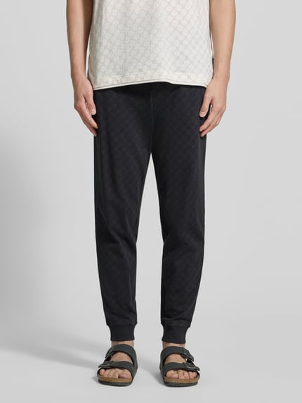 Mężczyzna nosi Sweatpants mit Logo-Muster und elastischem Bund od JOOP! Collection, czarna bawełna, krój regular fit, widok z przodu, zdjęcie całej sylwetki