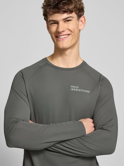 Męski model nosi Longsleeve z nadrukiem label-Print model 'SORONA' od HALO, krój regular fit, okrągły dekolt, kolor szary, zbliżenie na górną część ciała. Długość pleców w rozmiarze M: 66 cm.