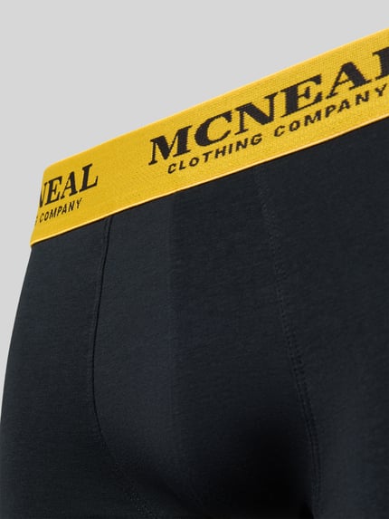 Produktfoto, Trunks mit elastischem Bund im 5er-Pack von MCNEAL, schwarze Baumwoll-Elasthan-Mix-Oberfläche, gelber Bund mit Logo, körpernahe Passform