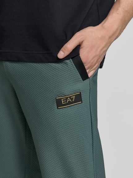 Männermodel trägt Regular Fit Sweatpants mit Strukturmuster von EA7 Emporio Armani, Elastischer-Material-Mix, Eingrifftaschen, Nahaufnahme Oberkörper.
