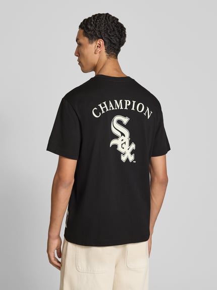 Männermodel trägt Relaxed Fit T-Shirt aus reiner Baumwolle von Champion in Schwarz mit Statement-Print, Rückenansicht, Nahaufnahme Oberkörper.