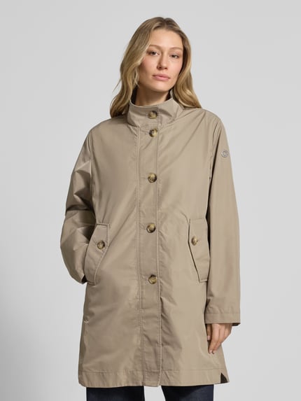 Frauenmodel trägt Mantel mit Stehkragen und Knopfleiste von Fuchs Schmitt in Beige, glatte Textur, Eingrifftaschen, Ganzkörperansicht von vorne.