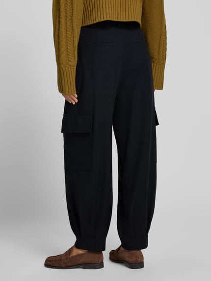 Frauenmodel trägt schwarze Cargo-Hose mit weitem Bein – curated by Vera van Erp von Style Icon Collection, Material-Mix, lockerer Schnitt, Ganzkörperansicht Rückansicht.