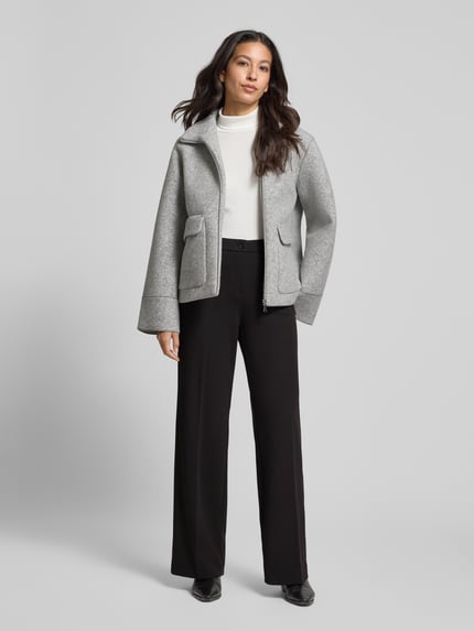 Vrouwenmodel draagt Wide Leg Bundfaltenhose met steekzakken model 'Hillda' van STEHMANN, zwart, full body van voren, materiaal-mix met stretch, knoop- en ritssluiting, plooien, taillewijdte 41 cm in maat 36, binnenbeenlengte 83 cm in maat 36.