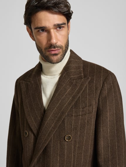 Männermodel trägt Mantel aus Woll-Mix mit Pattentaschen von Christian Berg Men, braun, dezentes Nadelstreifenmuster, Nahaufnahme Oberkörper. Regular Fit, Reverskragen, Knopfverschluss, Zweireiher, Allover-Look, strukturierte Oberfläche, Kontext: Rückenlänge 104 cm, Schulterbreite 47 cm, Brustweite 57 cm, Ärmellänge 68 cm.