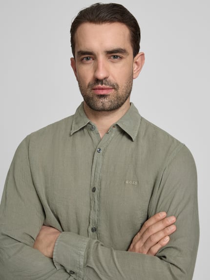 Männermodel trägt Regular Fit Freizeithemd aus reinem Leinen Modell 'RELEGANT' van BOSS in effen lichtgroen flammgaren met kentkraag, label stitching, lange mouw, 2-knop manchet, doorlopende knopenrij, detailopname bovenlichaam.