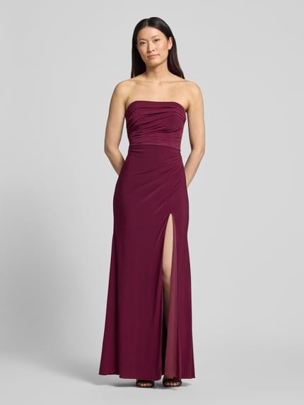 Frauenmodel trägt Slim Fit Abendkleid in Maxilänge mit Gehschlitz von Hey Kyla aus Elastischer-Material-Mix in Dunkelrot mit Raffungen, schulterfrei, glatte Textur, Ganzkörperansicht von vorne. Rückenlänge bei Größe 36: 132 cm, Brustweite: 28 cm.