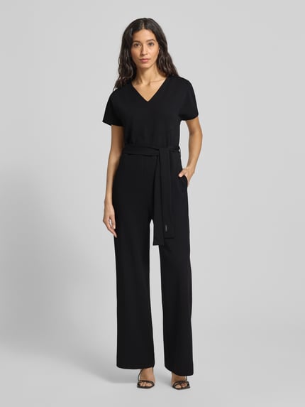 Frauenmodel trägt Jumpsuit mit V-Ausschnitt von Calvin Klein Womenswear, schwarzer Material-Mix mit Stretch-Anteil, Taillengürtel, lockerer Schnitt, Nahtreißverschluss, Ganzkörperansicht von vorne. Rückenlänge 39 cm, Brustweite 46 cm, Gesamtlänge 108 cm, Innenbeinlänge 77 cm bei Größe S.