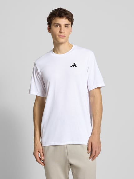 Männermodel trägt weißes T-Shirt mit Label-Print von adidas Training, Material-Mix mit Baumwoll-Anteil, Regular Fit, Nahaufnahme Oberkörper.