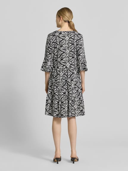 Frauenmodel trägt Minikleid mit Tunika-Ausschnitt von Christian Berg Woman Selection, Schwarz-Weiß-Muster, reine Baumwolle, taillierte Passform, halbarm, Rückansicht Ganzkörperansicht.