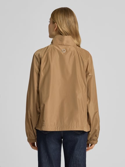 Frauenmodel trägt Jacke mit elastischen Abschlüssen und Stehkragen von Fuchs Schmitt in Braun, Gerader-Schnitt, Raglanärmel, Rückenansicht. Rückenlänge 56 cm, Schulterbreite 38 cm, Brustweite 48 cm, Ärmellänge 43 cm, Seitliche Reißverschlusstaschen, glatte Textur. Ganzkörperansicht Rückansicht.