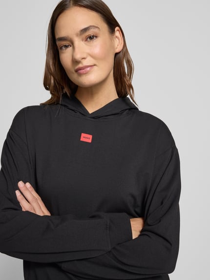 Vrouwenmodel draagt Regular Fit Hoodie uit katoen-modal-mix model 'SIGNATURE' van HUGO, zwart, label detail, close-up bovenlichaam.