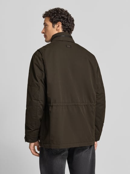 Männermodel trägt Jacke mit Stehkragen und Pattentaschen von camel active in Dunkelbraun, glatte Textur, Ganzkörperansicht Rückansicht. Rückenlänge 79 cm, Schulterbreite 44 cm, Brustweite 65 cm, Ärmellänge 71 cm, Regular Fit, Knopfleiste, Ärmelriegel.