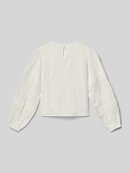 Mädchen trägt Blusenshirt mit Rundhalsausschnitt von Mango, Reine Baumwolle, Lockerer Schnitt, Schlüsselloch-Ausschnitt, Raffungen, Rückenlänge 44 cm, Ärmellänge 52 cm, weiße Farbe, strukturierte Oberfläche, Ganzkörperansicht Rückansicht.