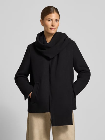 Frauenmodel trägt Regular Fit Kurzmantel mit Schalkragen Modell 'UNALAURA' von VERO MODA in Schwarz, glatte Struktur, Damen Teddy- / Webpelzjacke, Nahaufnahme Oberkörper.