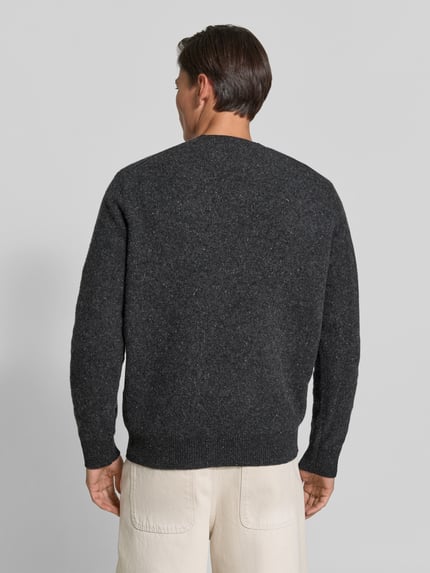 Męski model nosi sweter wełniany 'Wollpullover mi gerippten Abschlüssen' od ANNARR, czarna melanżowa wełna, luźny krój, okrągły dekolt, prążkowane wykończenia, długość tyłu w rozmiarze M: 66 cm, widok całej sylwetki z tyłu.