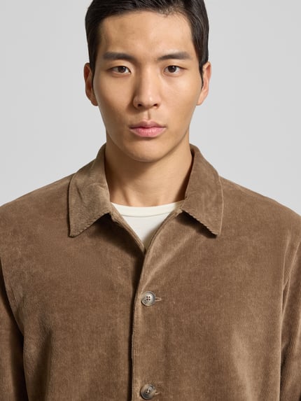Mannenmodel draagt Regular Fit Hemd aus reiner Baumwolle van Marc O'Polo in effen bruin corduroy met knopen en borstzak, Nahaufnahme bovenlichaam.