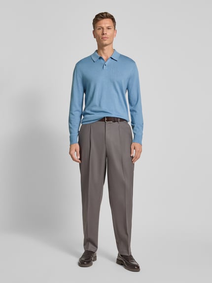 Männermodel trägt Regular Fit Strickpullover aus Woll-Mix von CK Calvin Klein in Blau mit Polokragen, Knopfleiste, Label-Stitching, Gerippte-Abschlüsse, Rückenlänge 68 cm, Ärmellänge 69 cm, Ganzkörperansicht von vorne.