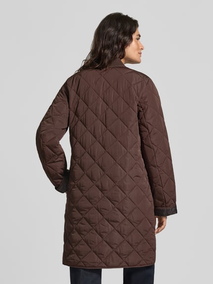 Frauenmodel trägt Slim Fit Steppmantel mit aufgesetzter Eingrifftasche von Jake*s Casual in Braun mit Stehkragen und Rautenstepp, Ganzkörperansicht Rückansicht.