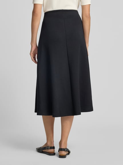 Vrouwenmodel draagt Midirok met elastische band van Christian Berg Woman in zwart, elastische materiaalmix met modal, los model, midilengte, bandwijdte bij maat S 80 cm, achteraanzicht op volledige lengte.