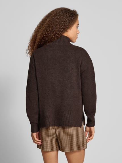 Frauenmodel trägt Rollkragenpullover mit Teilungsnaht von PIECES in brauner Melange Strickoptik, Strukturmuster, Longline, Ganzkörperansicht Rückansicht.