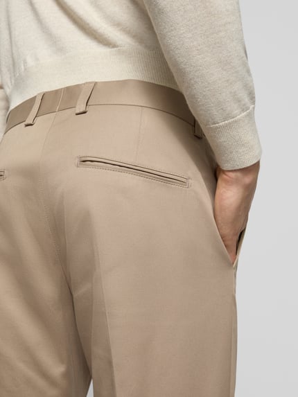 Männermodel trägt Stoffhose mit Gesäßtaschen Modell 'Tenuta' von Tiger Of Sweden, beiger Baumwoll-Elasthan-Mix, Detailaufnahme Rücken.