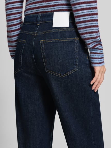 Frauenmodel trägt Barrel Jeans aus Baumwoll-Mix Modell 'Mari Cosmo' von OPUS PANTS in dunklem Blau mit sichtbarer Textur, Ganzkörperansicht Rückansicht. Damen Barrel Jeans von OPUS PANTS.