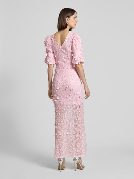 Vrouwenmodel draagt avondjurk met applicatie, slim fit maxi-jurk met v-vormig decolleté en pofmouwen, model 'BEATE' van YAS, ruglengte 145 cm, borstwijdte 36 cm, mouwlengte 38 cm, detailrijke textuur, zachte roze tint, rugaanzicht, geheel lichaam.