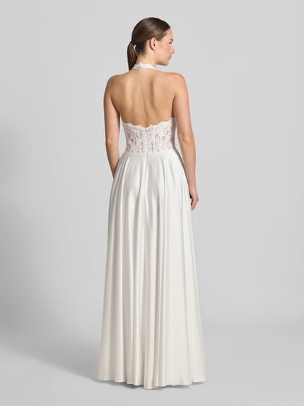Frauenmodel trägt Brautkleid mit floralem Stitching von Mascara in Weiß, taillierte Passform, Neckholder, Ganzkörperansicht Rückansicht.
