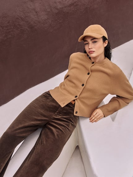 Frauenmodel trägt Strickjacke aus Wolle mit Rundhalsausschnitt von Jake*s Casual, Regular-Fit, Knopfleiste, Rückenlänge 50 cm, Ärmellänge 70 cm, Reine Wolle, warme Brauntöne, glatte Struktur, Ganzkörperansicht von vorne.