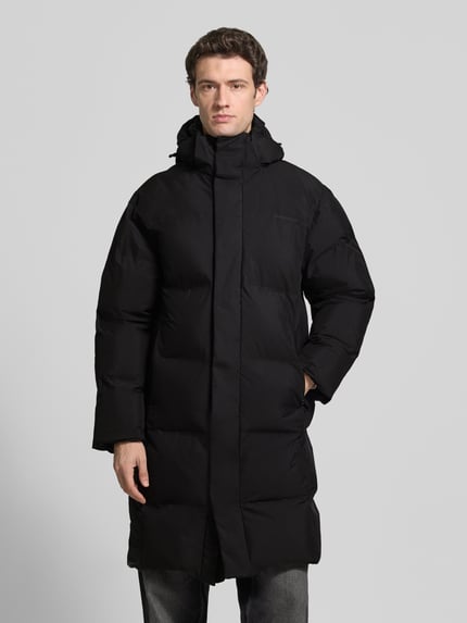 Mannelijk model draagt zwarte Regular Fit Steppmantel met steekzakken van Lindbergh, lange mouwen, capuchon, vooraanzicht volledige lichaamsopname.