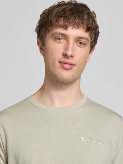 Männermodel trägt T-Shirt mit Label-Stitchings und Rundhalsausschnitt von CHAMPION, Reine Baumwolle, Regular-Fit, Nahaufnahme Oberkörper.