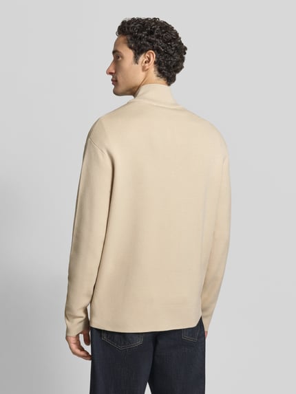 Männermodel trägt Strickjacke mit Zweiwege Reißverschluss von Selected Homme in uni Beige, langarm, Regular Fit, Longline, Struktur, Ganzkörperansicht Rückansicht.